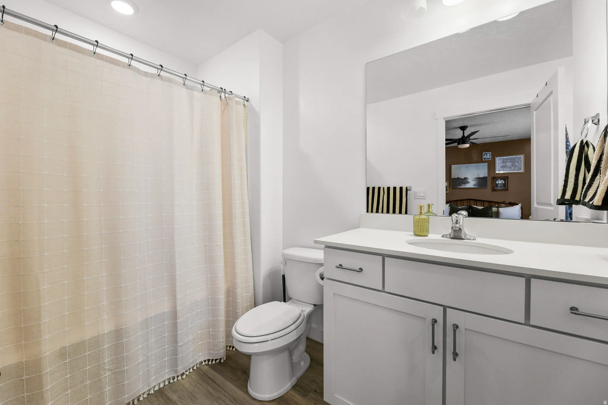 Bathroom featuring wood-finish flooring and a white vanity with an integrated sink and brushed nickel hardware