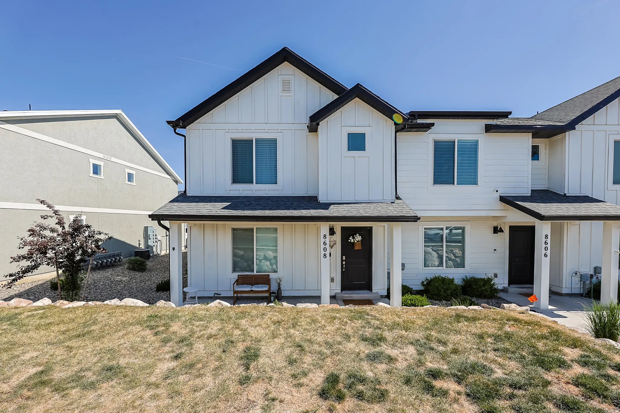 Modern farmhouse-style townhome featuring crisp white siding with black trim accents
