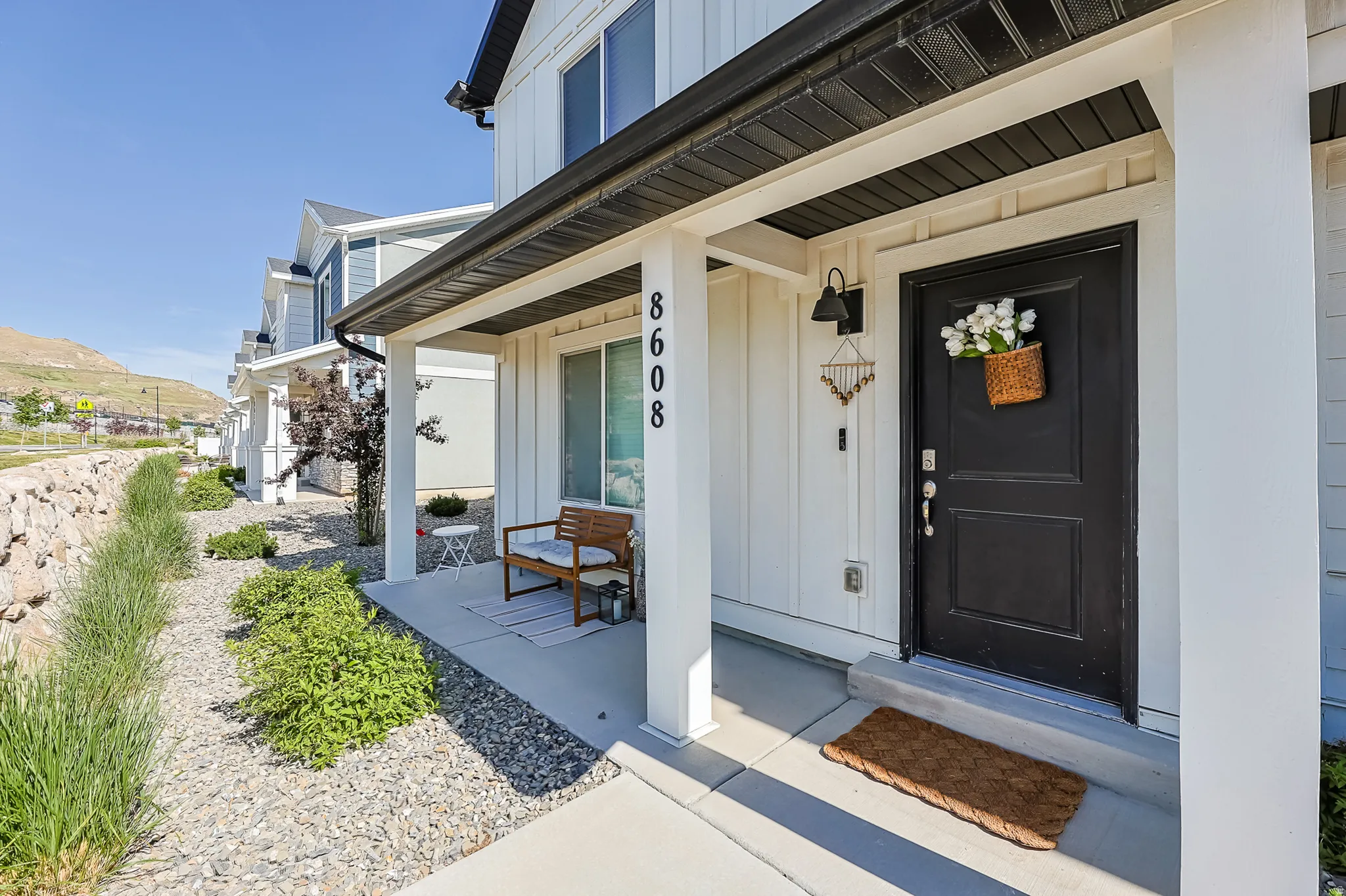 Front porch entry featuring a dark-paneled door, black exterior sconce, and white board and batten siding