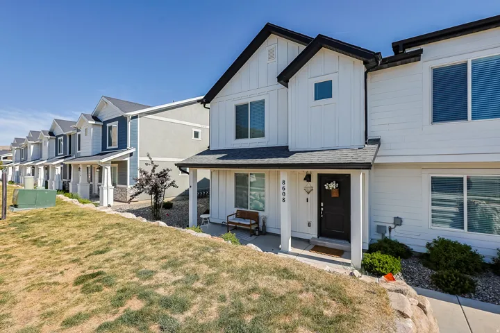 Modern white exterior with black trim, featuring a covered front porch and a dark entry door