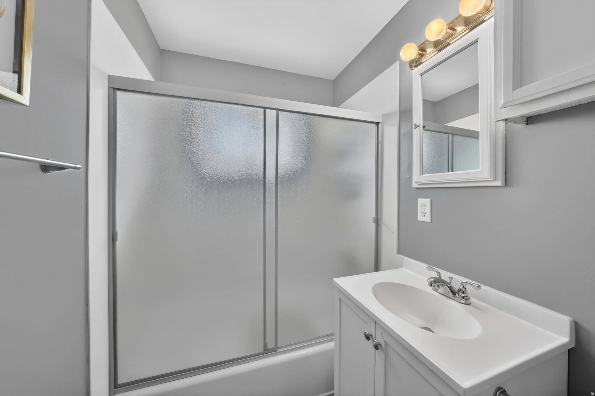 Bathroom featuring a white vanity with integrated sink, chrome faucet, and overhead lighting