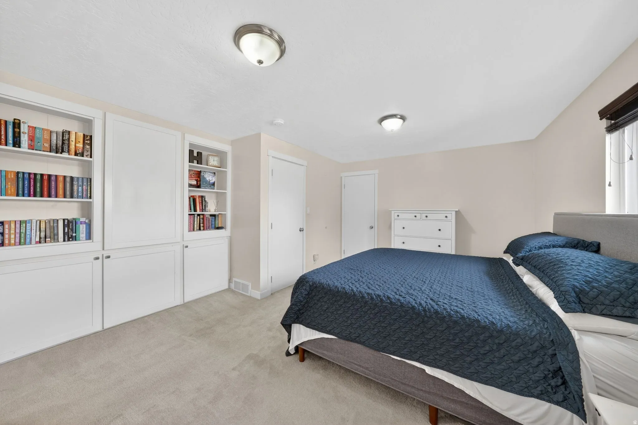 Neutral-toned room featuring wall-to-wall carpeting and built-in white cabinetry with shelving