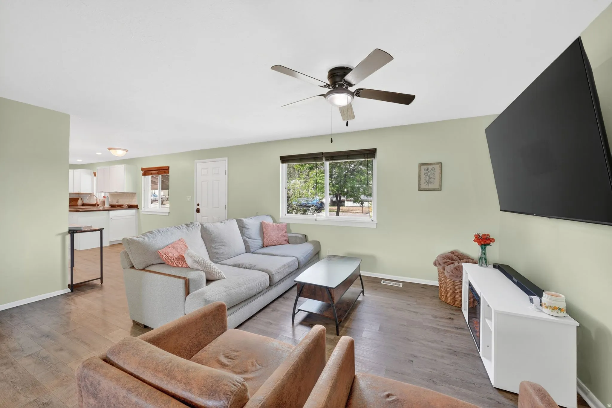 Living area featuring wood-finish flooring and a ceiling fan with integrated lighting