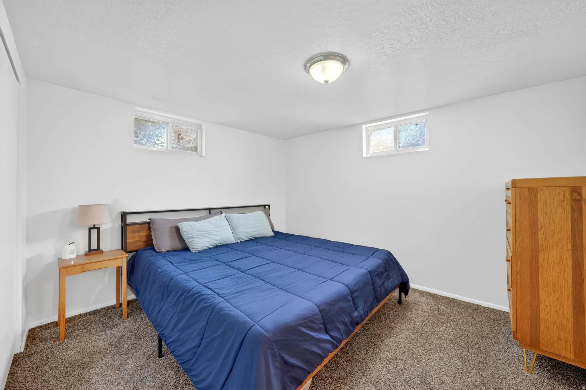 Carpeted room with a ceiling-mounted light fixture and two upper-level windows