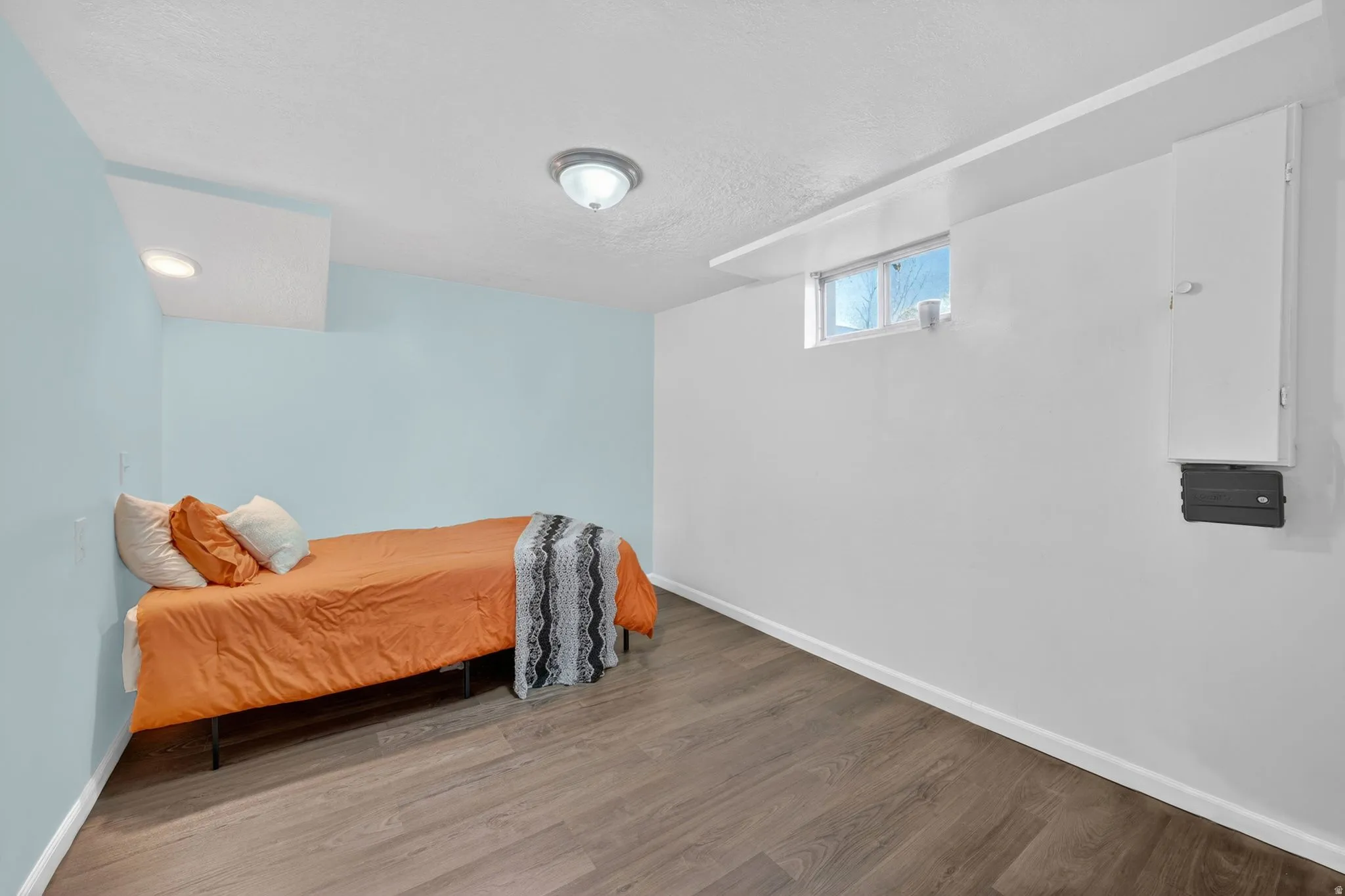 Room featuring light blue and white painted walls, wood-finish flooring, a flush-mount ceiling light, a recessed ceiling light, and a window with white trim