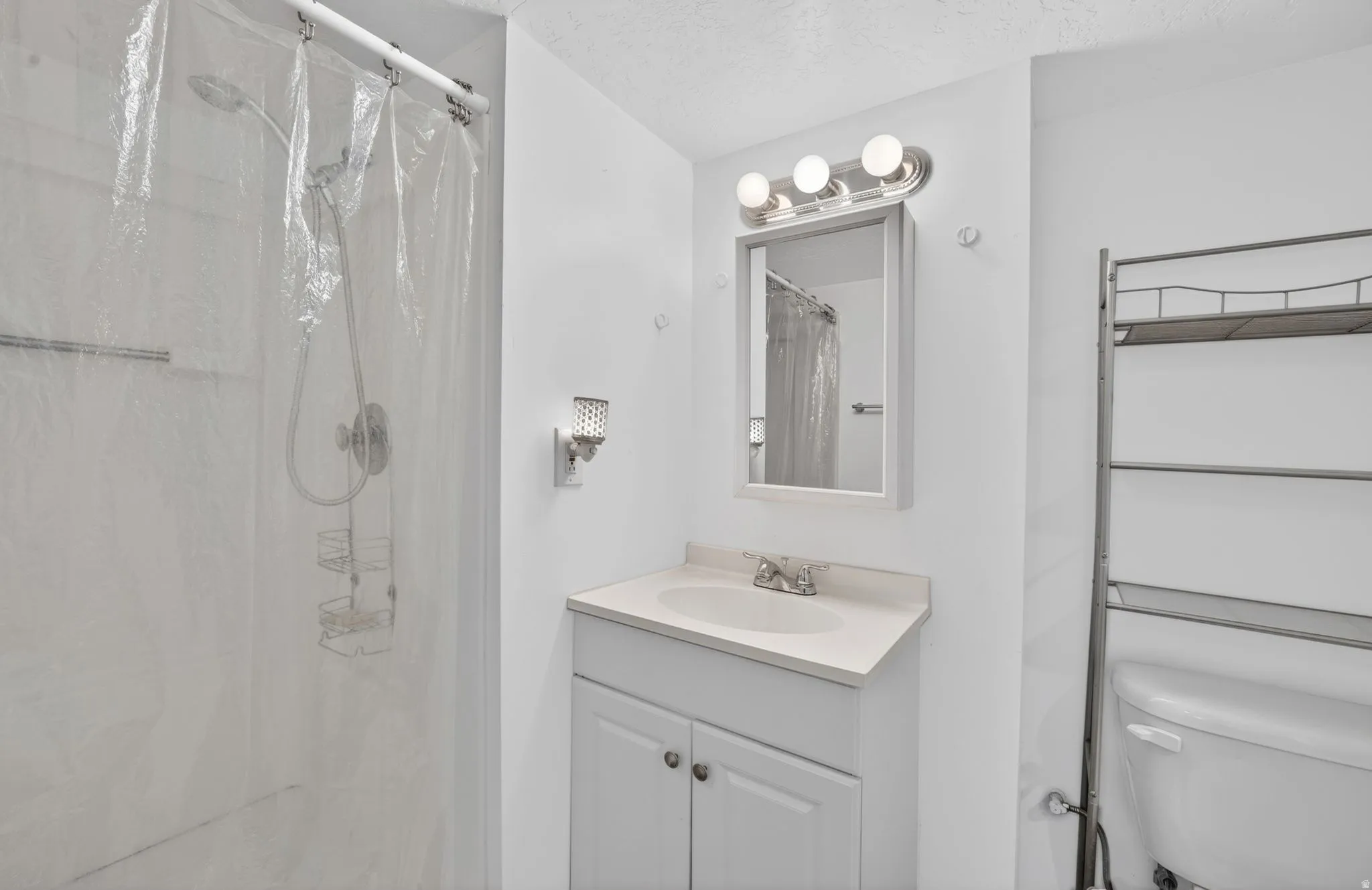 Bathroom featuring a white vanity with integrated sink, chrome faucet, and mirrored medicine cabinet