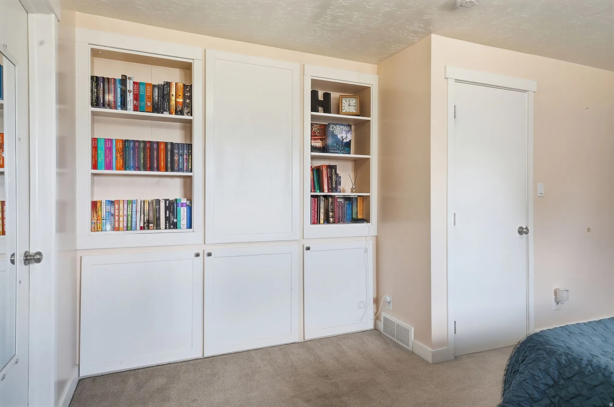 Built-in white cabinetry with open shelving and closed storage, complemented by light-colored wall paint and neutral carpeting