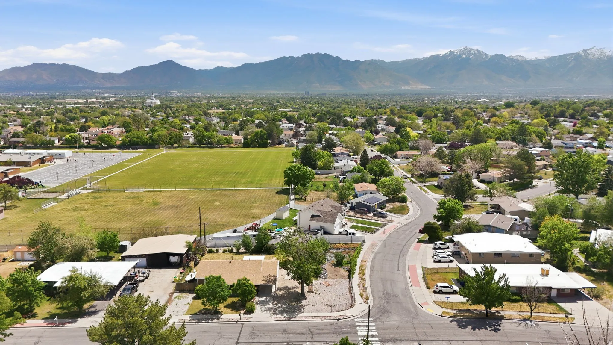 Residential neighborhood with mature trees, paved streets, and mountain scenery