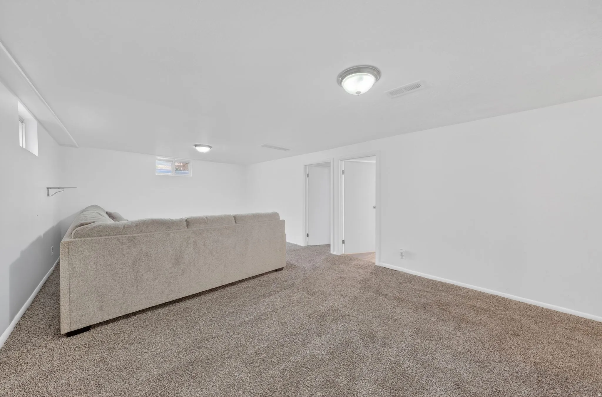 Spacious room featuring neutral carpeting, white walls, and two recessed windows