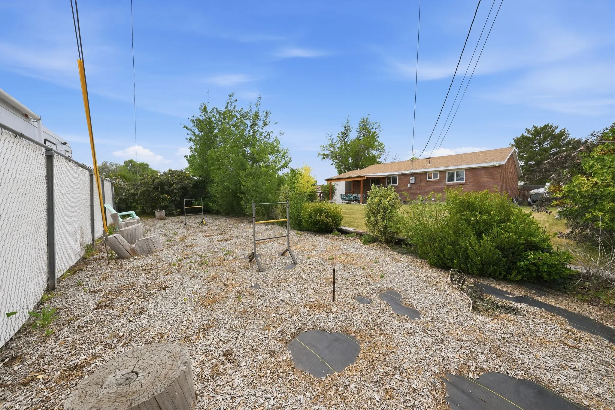 Expansive backyard featuring a chain-link fence, mature trees, and a brick exterior home in the background