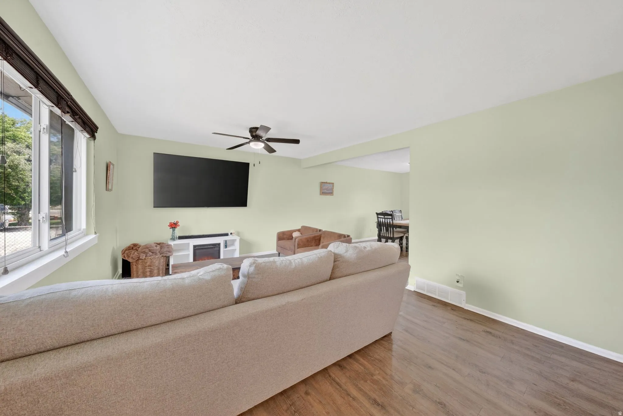 Living area featuring wood-finish flooring, light green wall paint, and white trim