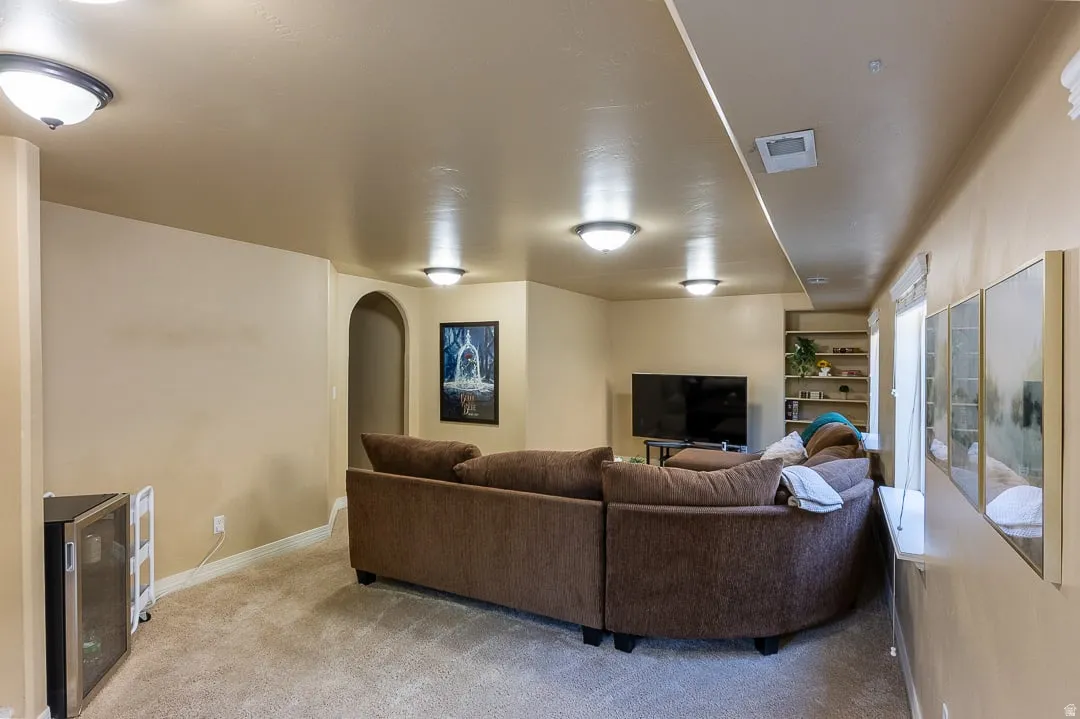 Expansive room featuring recessed lighting, a built-in archway, integrated shelving, and carpeted flooring