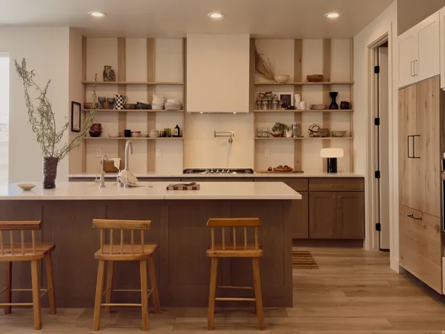 Modern kitchen featuring an expansive center island with seating, a gas range with a wall-mounted pot filler, open shelving, recessed lighting, and wood-finish flooring
