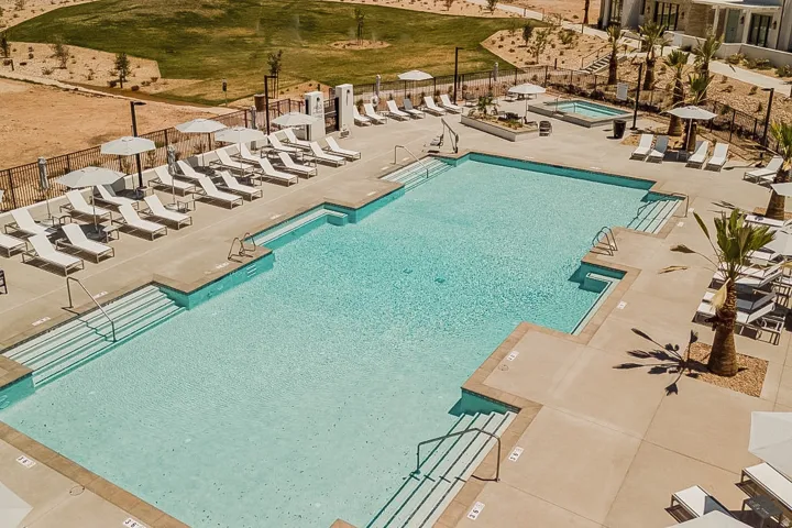 Expansive outdoor pool area featuring a large multi-level swimming pool, integrated spa, and surrounding concrete deck