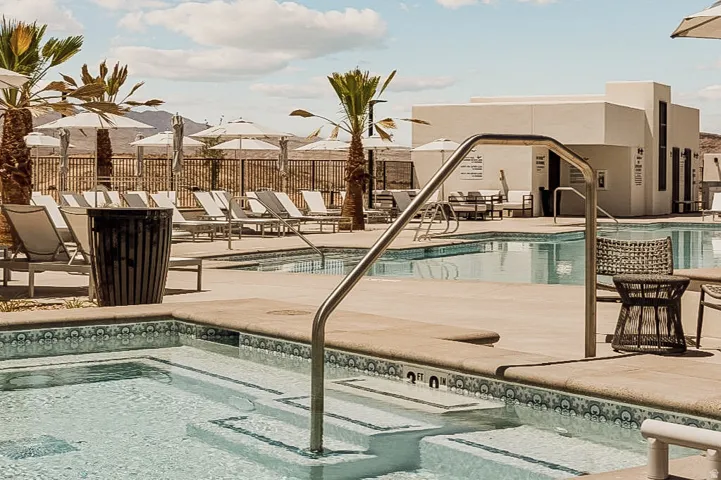 Resort-style pool area featuring a large swimming pool and an integrated spa with decorative tile accents