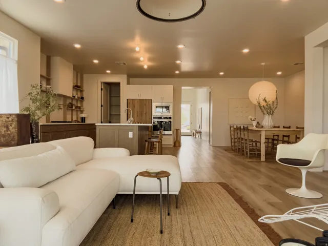Spacious open-concept interior featuring light wood-finish flooring, recessed lighting, and a kitchen with a central island and built-in appliances