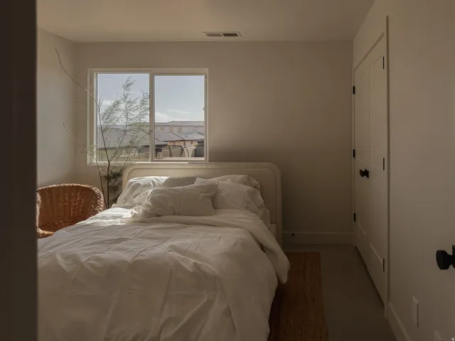 Bedroom featuring a white window frame, light-colored walls, and a white paneled door with black hardware