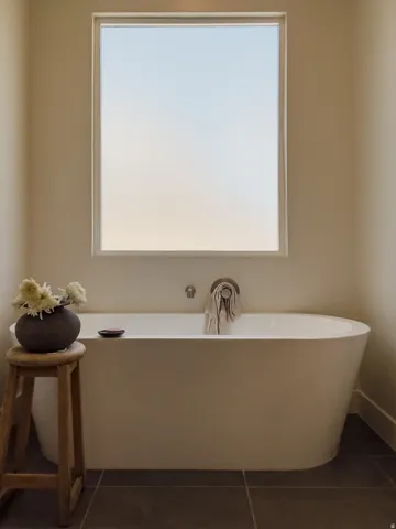 Freestanding soaking tub with wall-mounted plumbing fixtures