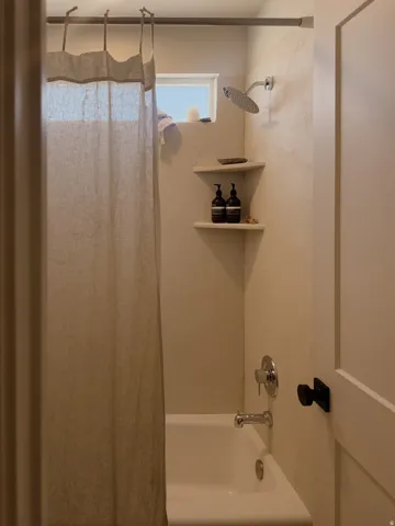 Bathtub-shower combination featuring a rainfall showerhead and chrome fixtures