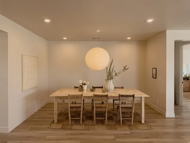 Recessed lighting illuminates this dining area, featuring wood-finish flooring and a contemporary pendant light fixture