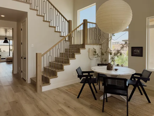 Open-concept interior featuring wood-finish flooring, a contemporary staircase with iron balusters and wood handrails, and tall windows