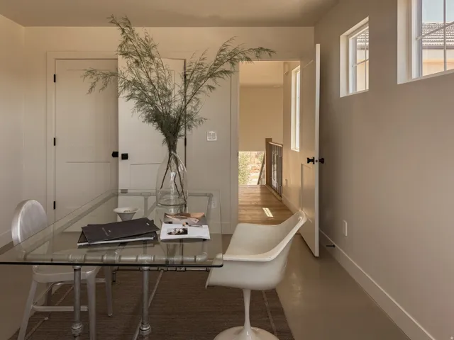Neutral tone walls with white trim, two white paneled doors with black hardware, and multiple windows providing natural light