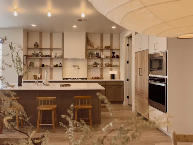 Kitchen featuring a spacious island with seating, a gas range with a pot filler, built-in stainless steel appliances, open shelving, and wood-finish flooring