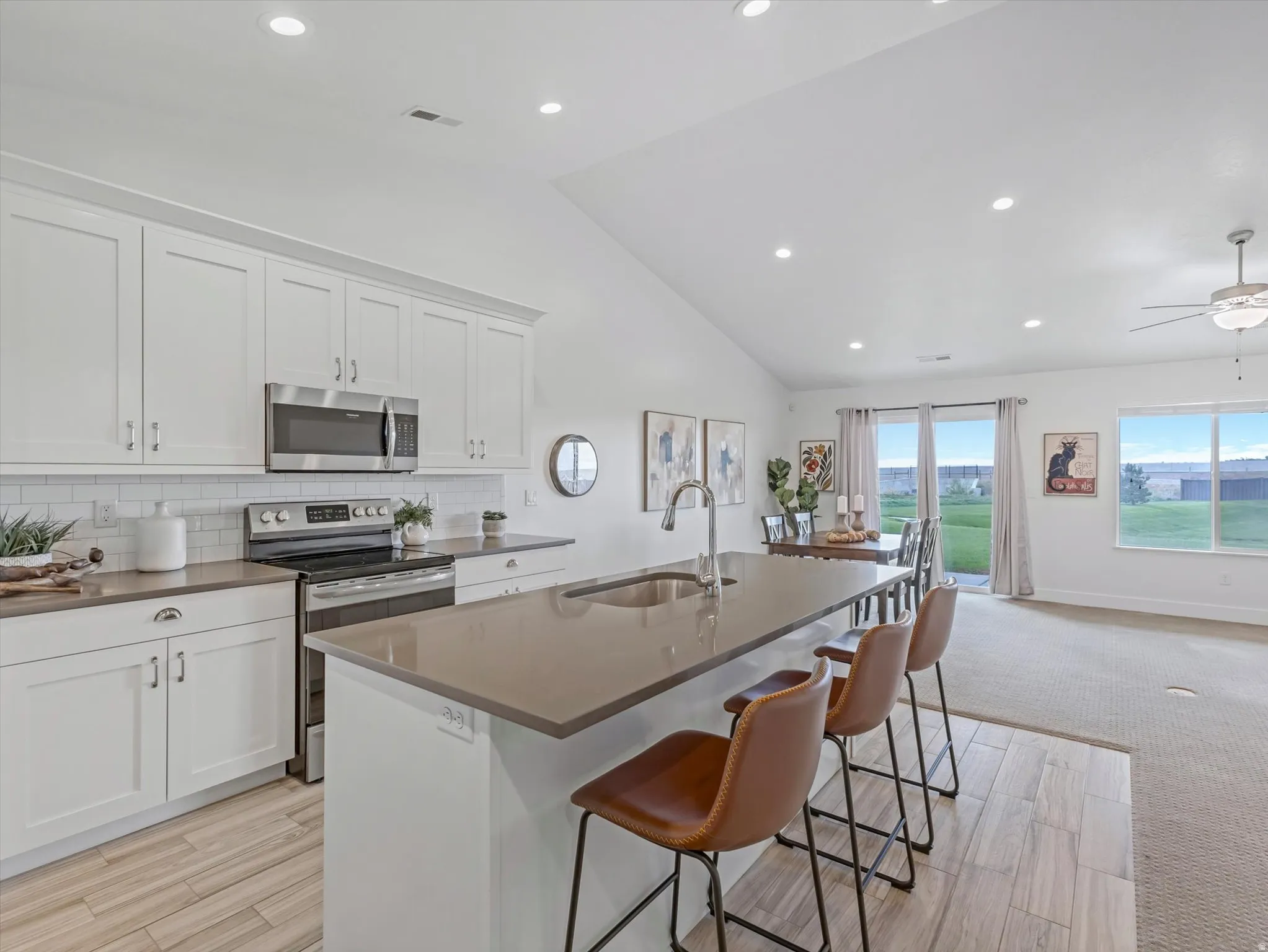 Modern kitchen featuring white shaker cabinetry, stainless steel appliances, a subway tile backsplash, and a large island with an undermount sink