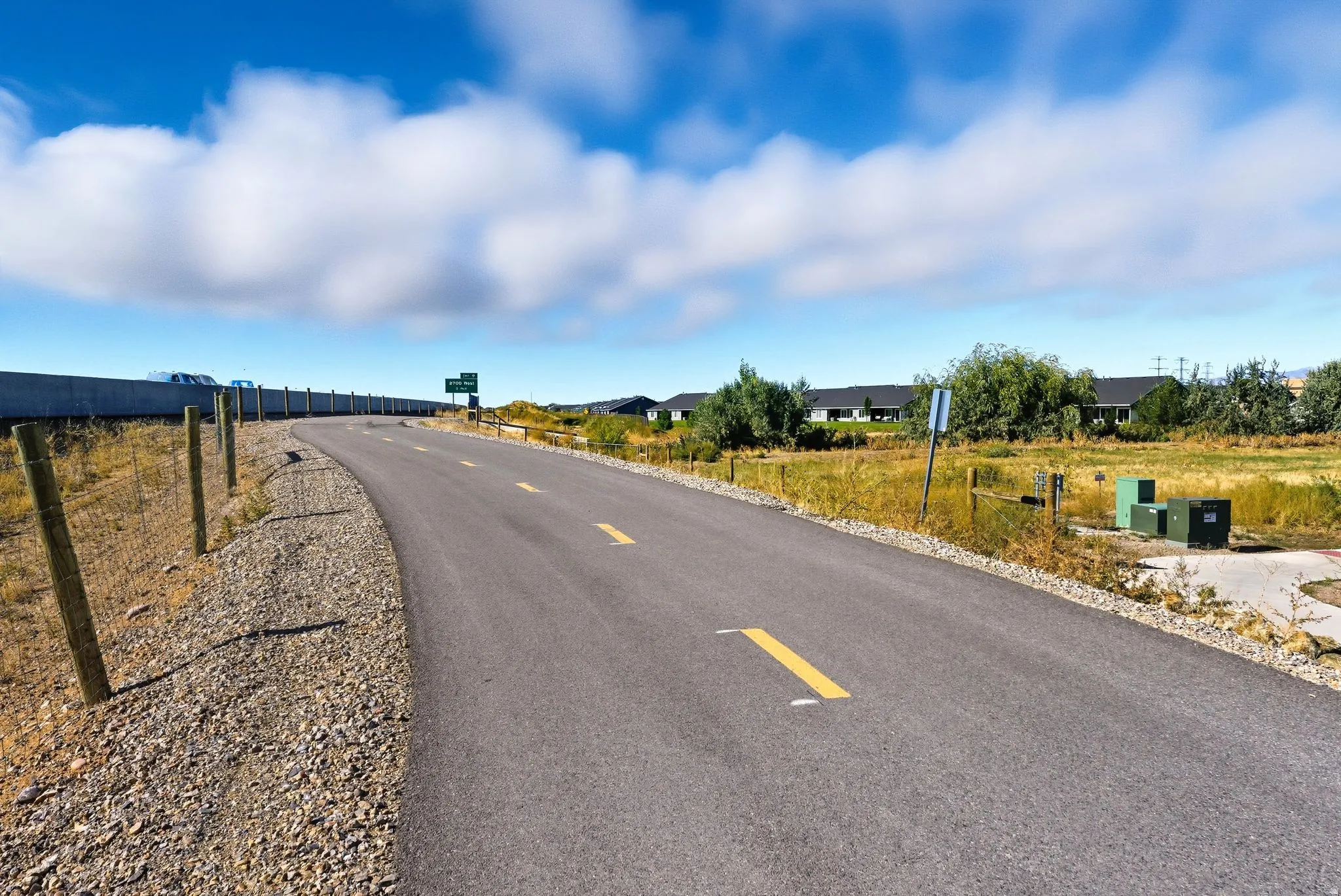 Paved pathway with central yellow dashed lines and perimeter gravel