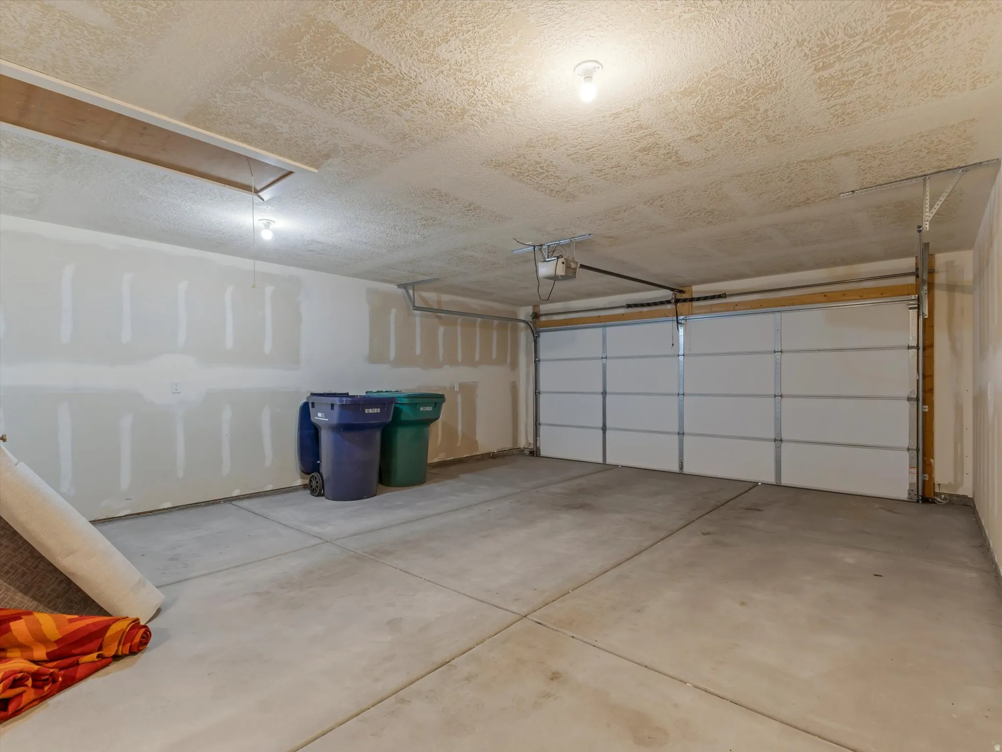 Spacious garage featuring a concrete floor, overhead lighting, and an automatic garage door opener
