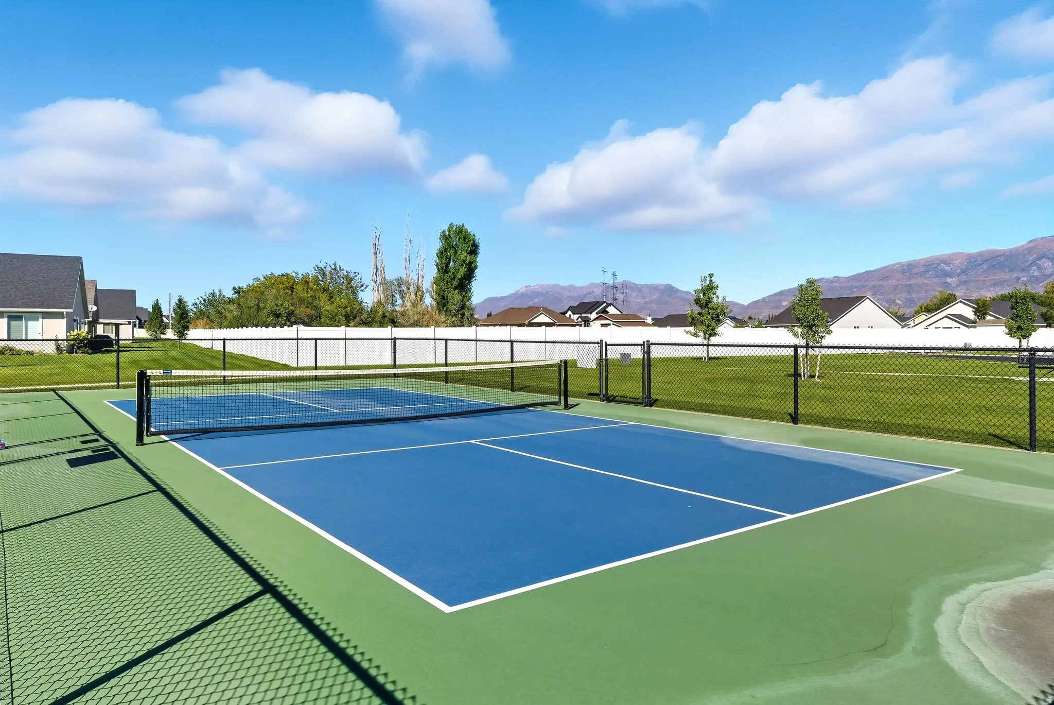 Outdoor court featuring blue and green playing surfaces with white boundary lines