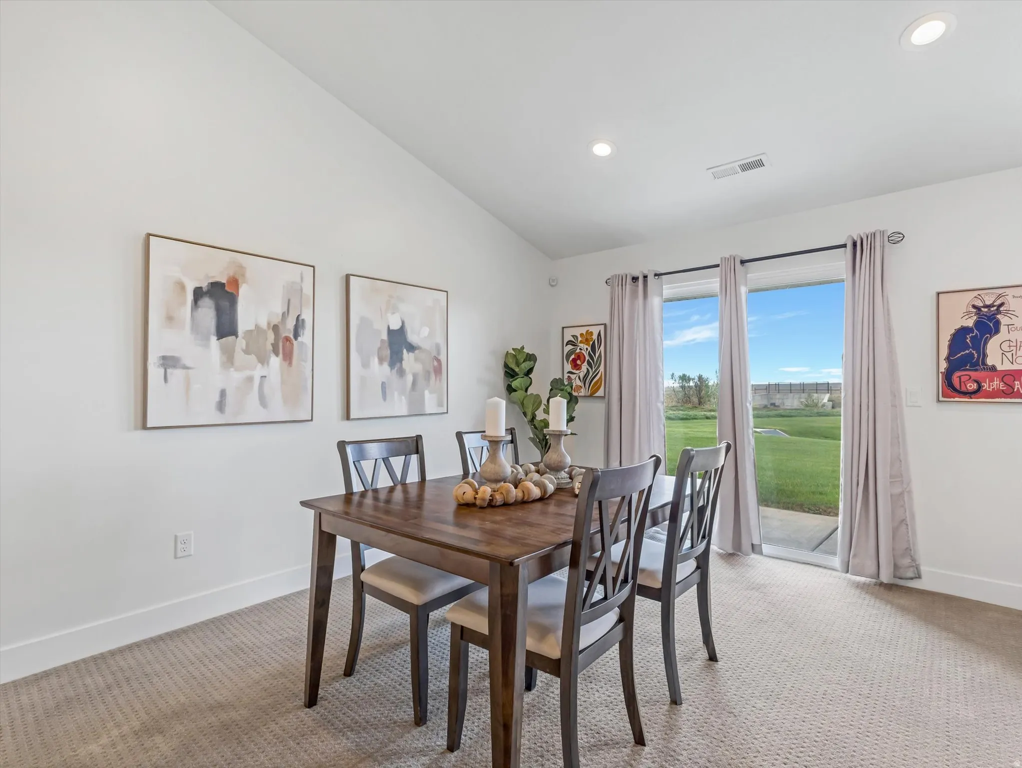 Dining area featuring a vaulted ceiling with recessed lighting, carpet flooring, and a sliding glass door providing exterior access