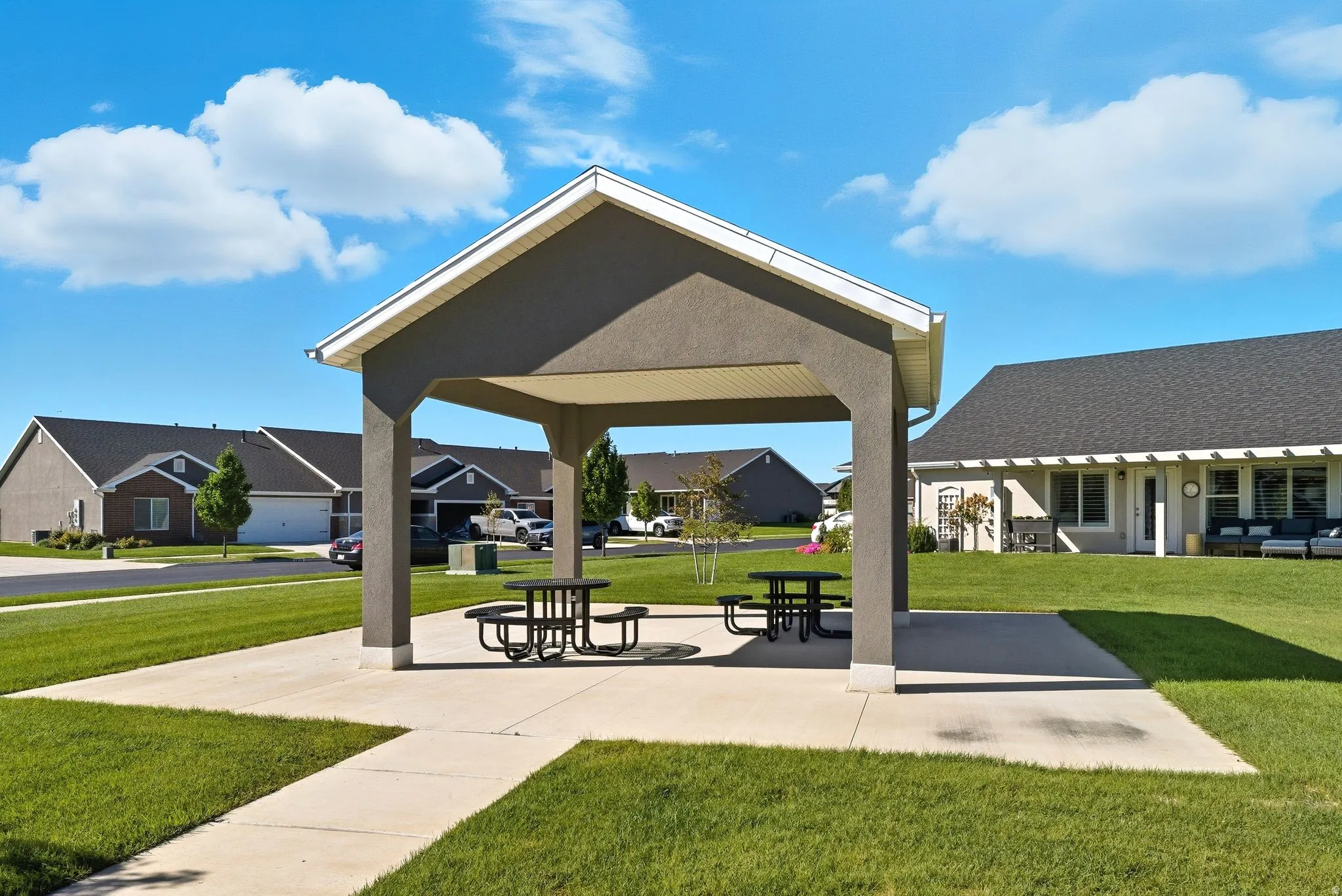 Central open-air pavilion featuring a gabled roof, concrete pad, and two picnic tables