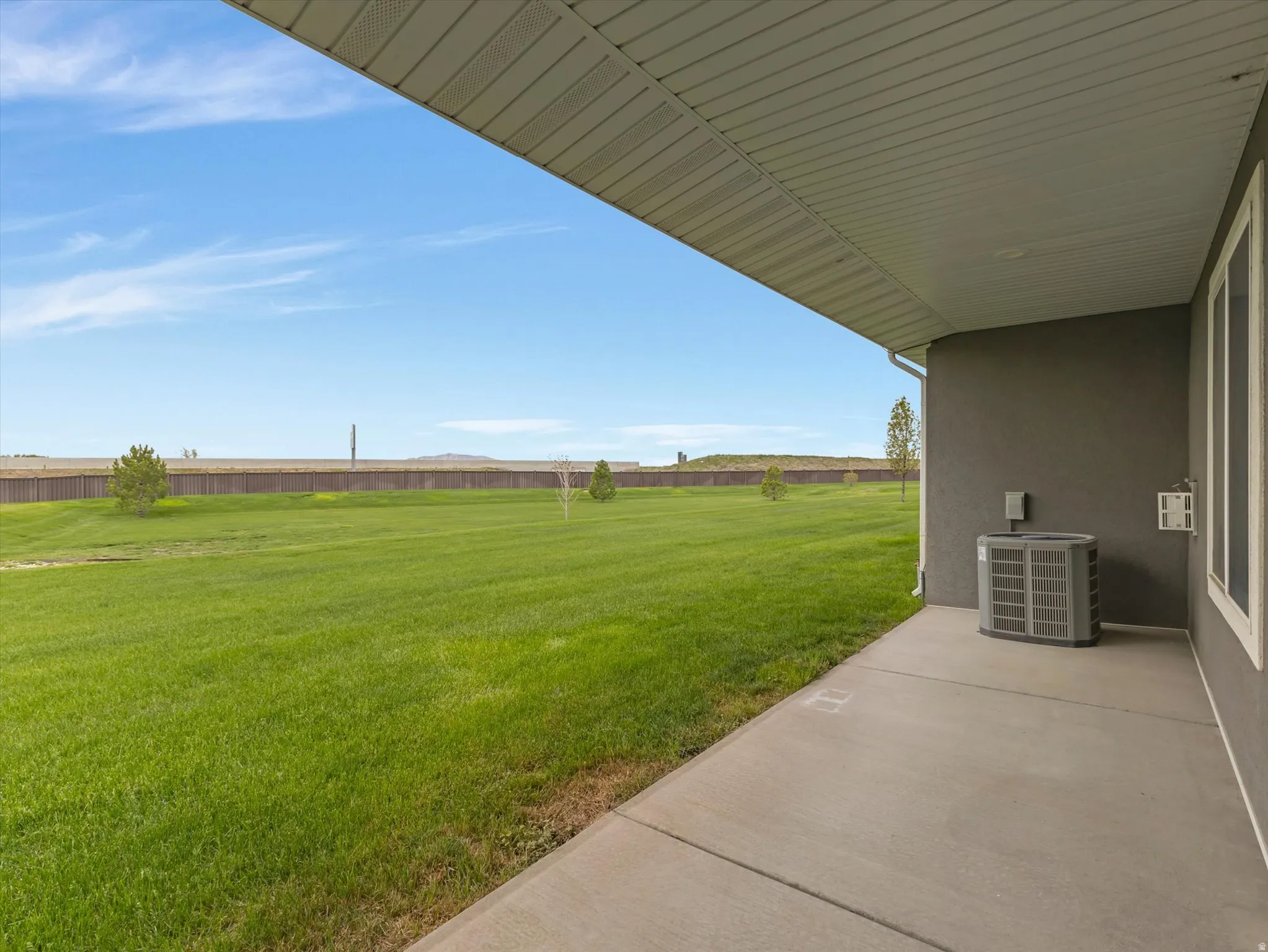 Concrete patio providing covered outdoor living, overlooking an expansive green lawn
