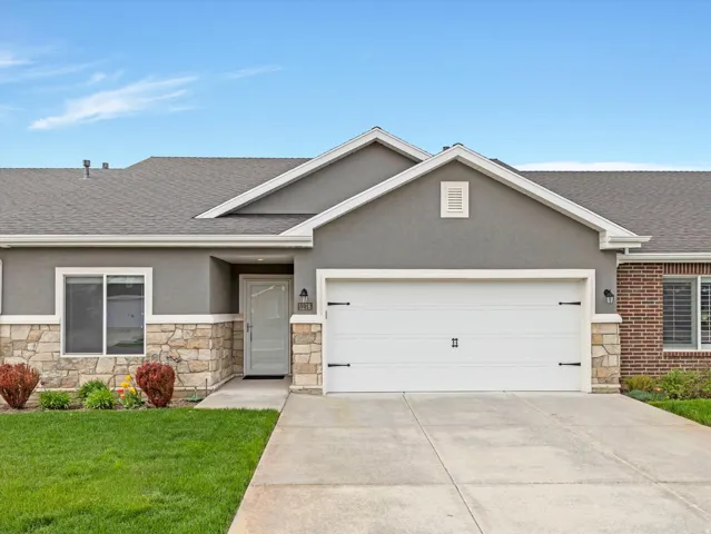 Stone veneer and stucco exterior featuring a two-car garage with decorative hardware