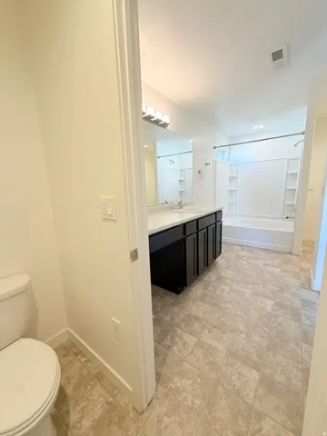 Master bathroom- featuring a dual-sink vanity with dark cabinetry, ample counter space, and a large mirror
