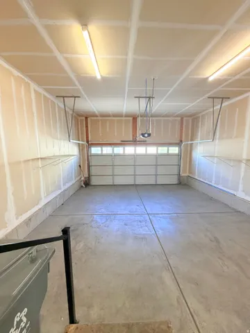 Spacious garage featuring a concrete floor, overhead lighting, and an automatic garage door opener
