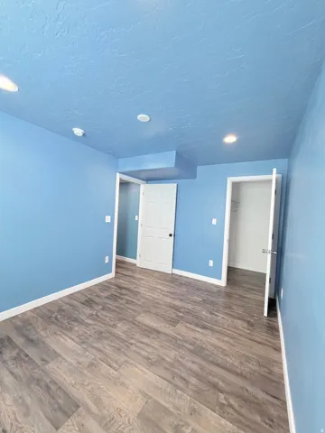 Spacious room featuring wood-finish flooring, recessed lighting, and bright blue walls
