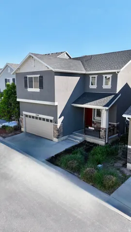 Contemporary-style exterior featuring a two-car garage, stone accents, and a covered porch with a red entry door