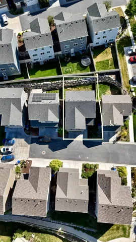 Aerial perspective showcasing a residential property with a gray shingle roof and a paved driveway