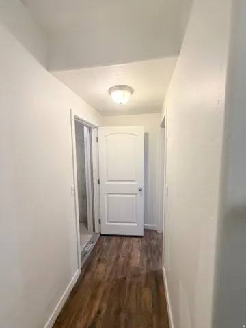 Hallway featuring wood-finish flooring, white painted walls, and an overhead dome light fixture