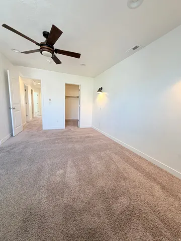 Master bedroom-Spacious carpeted room featuring a ceiling fan with integrated lighting, recessed lighting, and wall-mounted sconces
