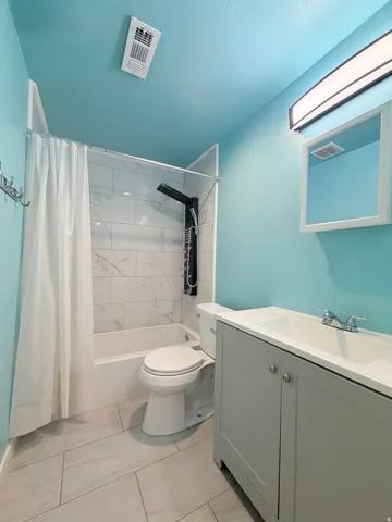 Bathroom featuring a shower/tub combination with white subway tile surround, a sleek black shower panel, and a white shower curtain