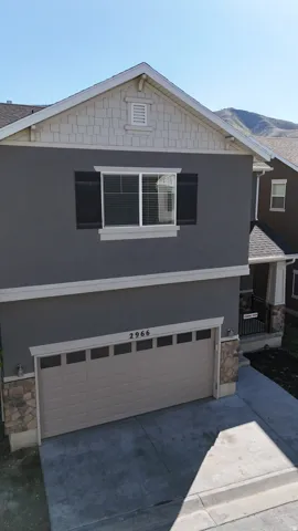 Contemporary residential exterior featuring a two-car garage, stone accents, horizontal siding, and a gabled roofline