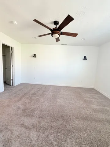 Spacious interior room featuring neutral-toned carpeting and white walls