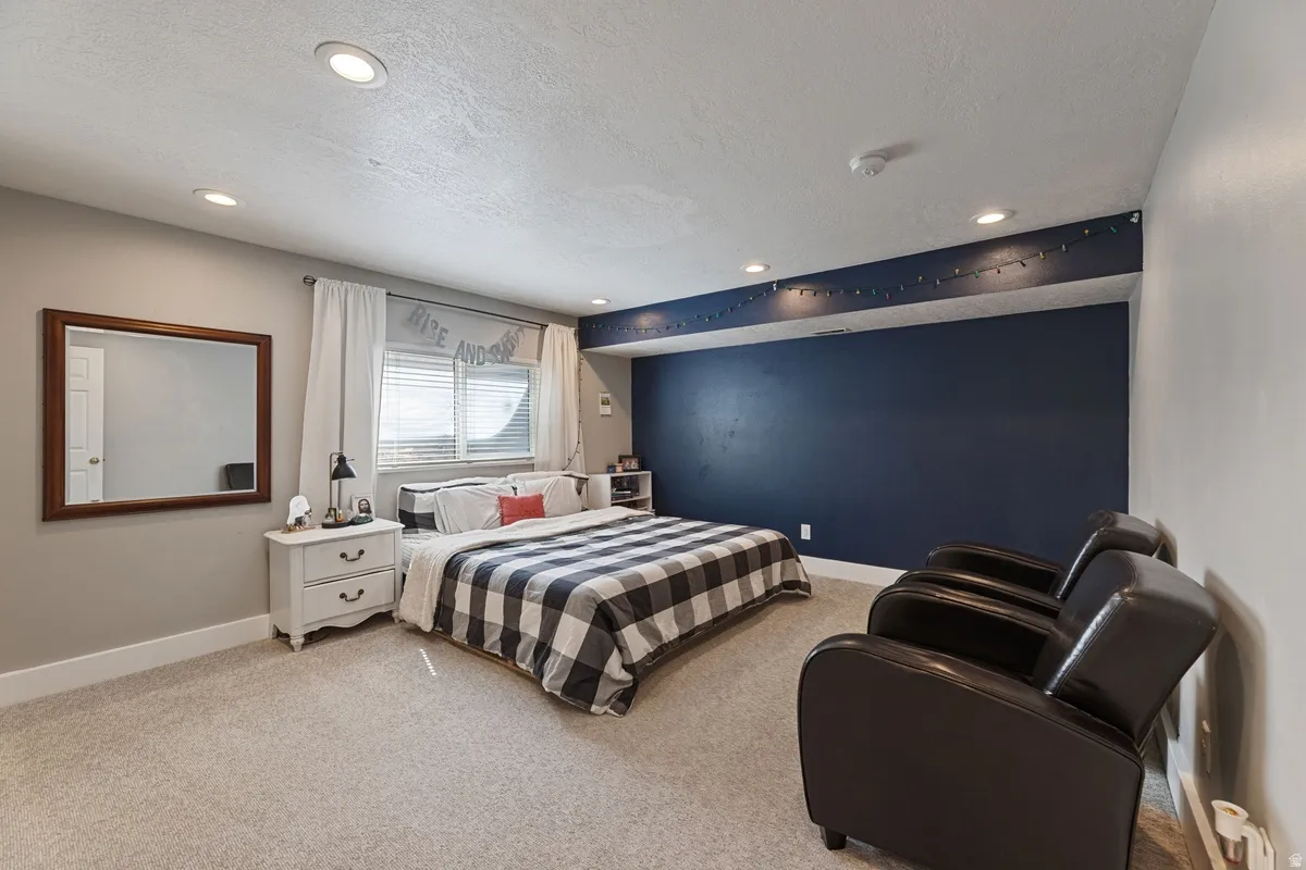 Spacious room featuring neutral carpeting, recessed lighting, a window with blinds, and a contrasting accent wall