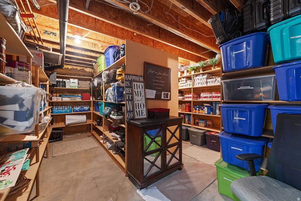 Expansive basement storage area featuring exposed wood ceiling joists and ample built-in shelving