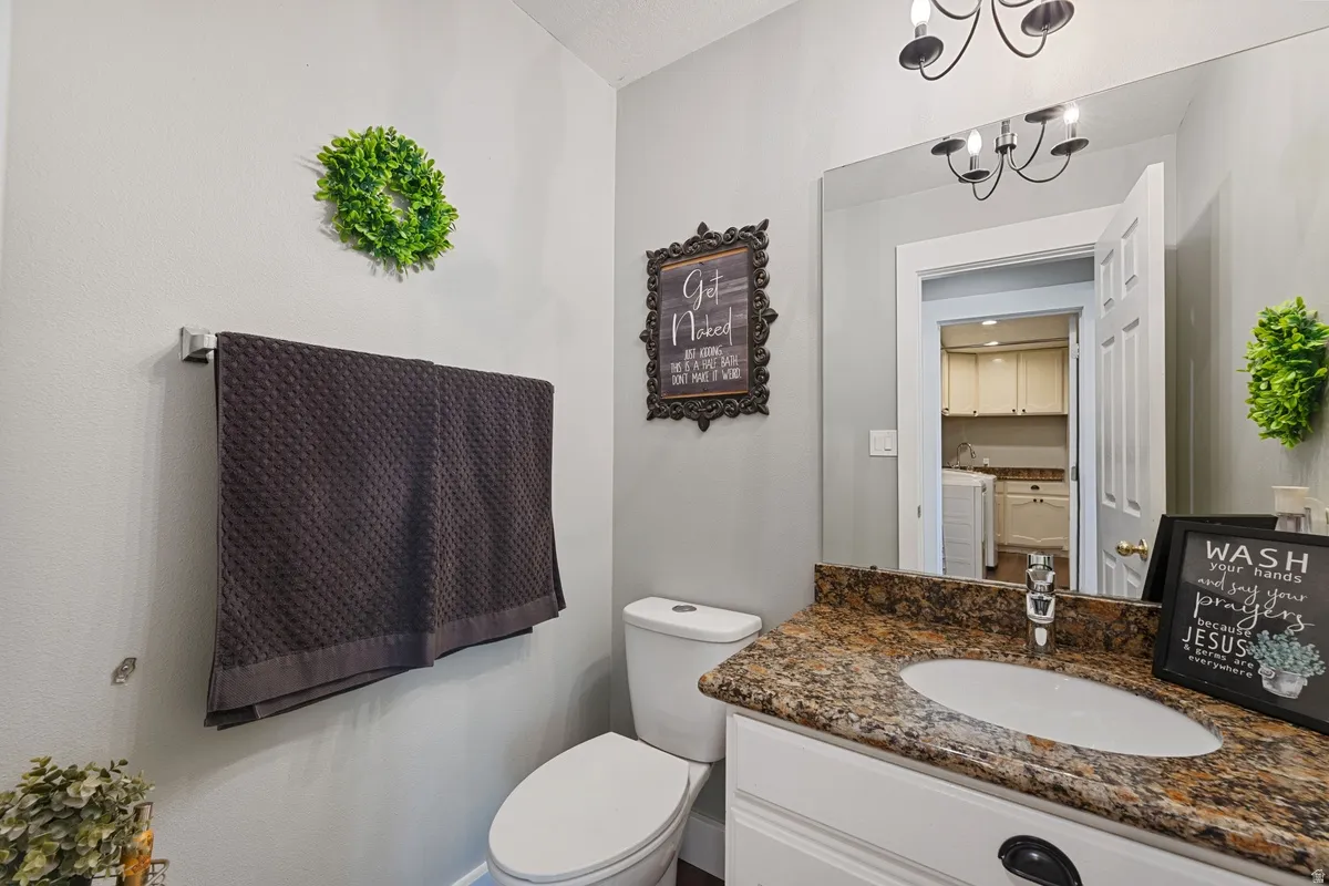 Bathroom featuring a vanity with a granular countertop, an undermount sink, and a framed mirror