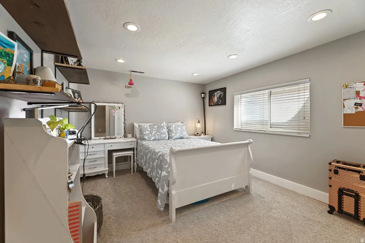 Comfortable sleeping area featuring recessed lighting, a window with horizontal blinds, and neutral wall tones