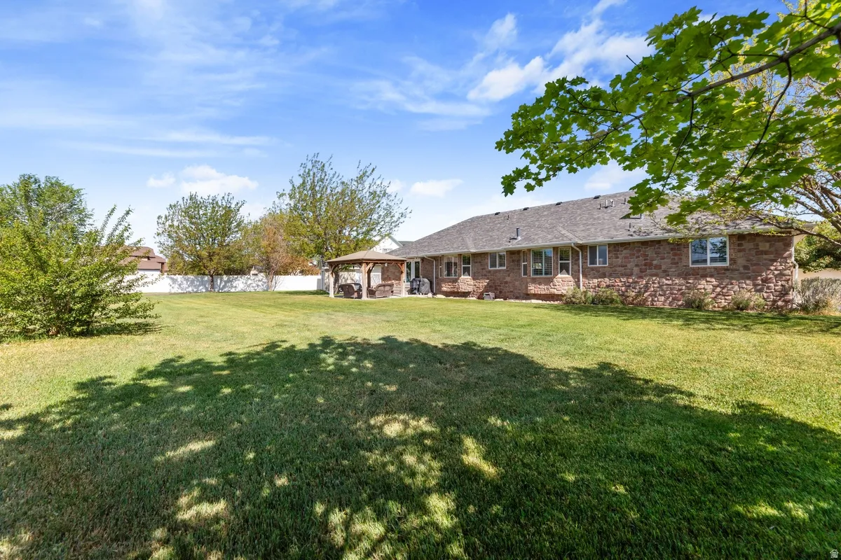 Expansive green lawn with mature trees and a white privacy fence